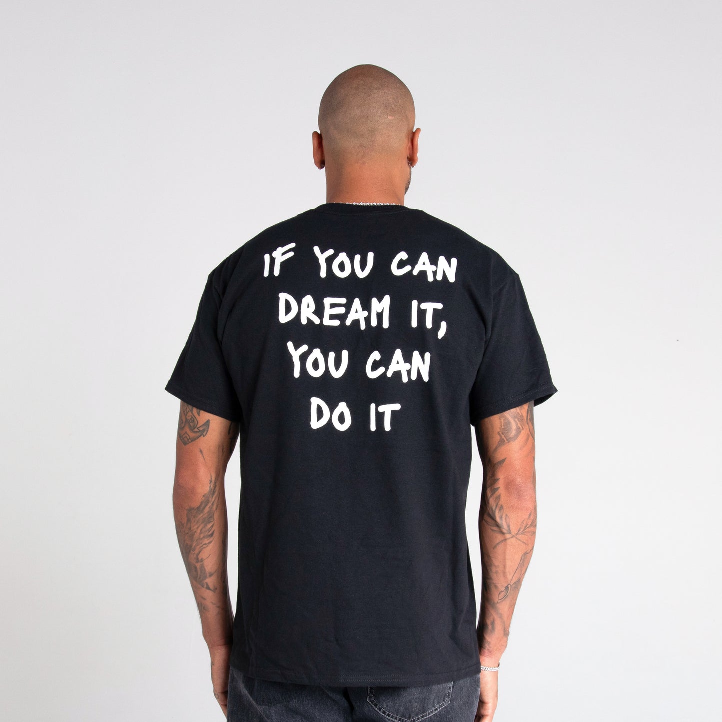 Logo distintivo sulla parte anteriore della maglia nera" "Frase iconica di Marcell Jacobs 'If you can dream it you can do it' in bianco sulla parte posteriore della maglia nera"