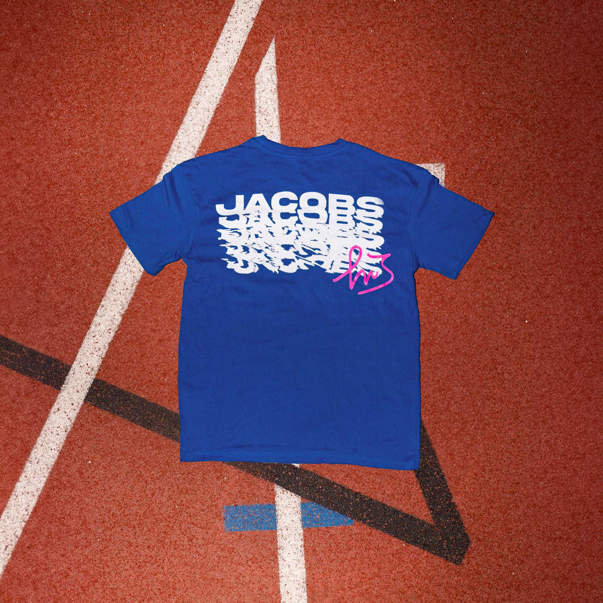 Logo distintivo sulla parte anteriore della maglia blu" "Schema ripetuto della scritta 'Jacobs' sulla parte posteriore della maglia blu in colore magenta con firma di Marcell Jacobs"